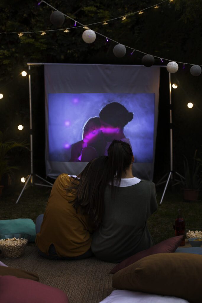 A couple enjoying the movie on an outdoor projector in their garden.